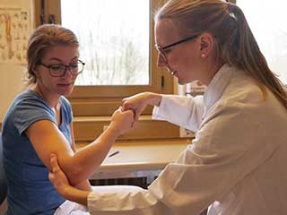Dr. Sophia Hünnebeck untersucht eine Patientin am Ellenbogen