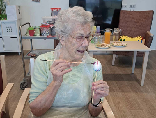 Eine Bewohnerin im Pflegeheim bemalt ein Osterei