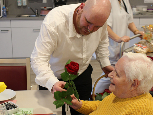 Betreuungsassistent Matthias Burmeister überreicht eine Rose an eine Bewohnerin | Immanuel Seniorenzentrum Elstal